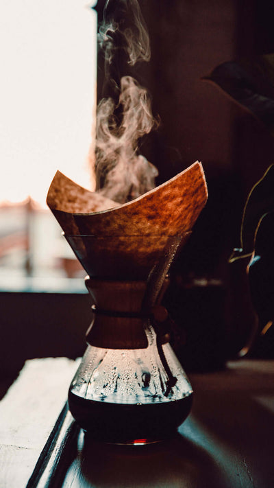 Central Bru hourglass dripper with pour over coffee filter, hourglass dripper is filled part way with coffee and hot steam is billowing from the top